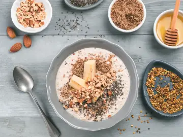 Avena con plátano, almendras picadas, chía y miel, rodeada de ingredientes.