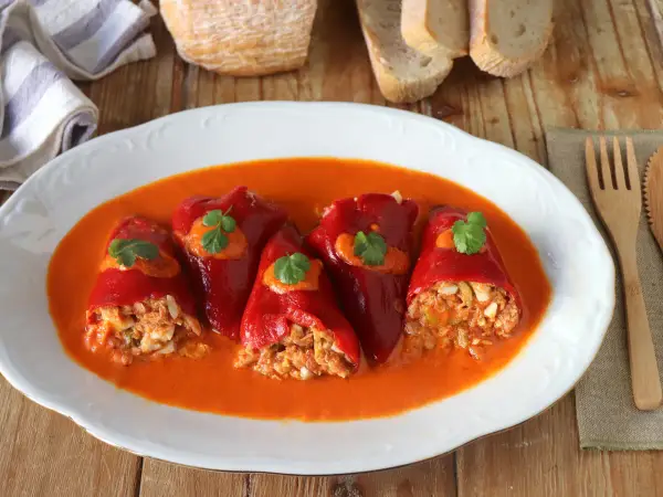 Pimientos del piquillo rellenos de carne y huevo en salsa de tomate, decorados con perejil.