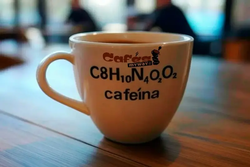 Taza de café blanca con la fórmula química de la cafeína y el texto "cafeína" impresos.